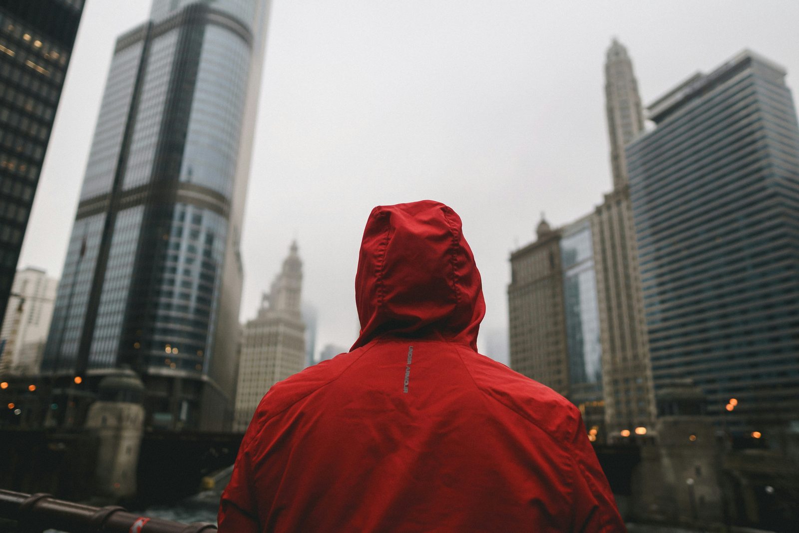 Homme en veste imperméable rouge à capuche dans une rue urbaine, illustrant la tendance athleisure